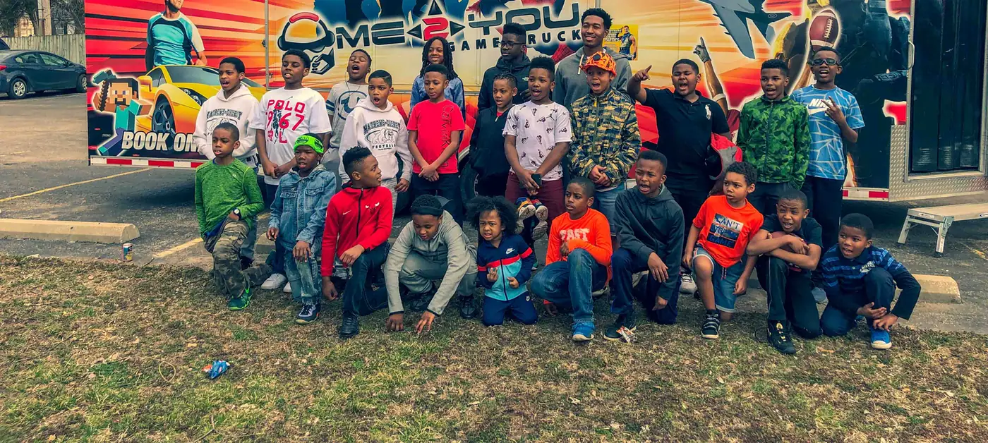 Kids gathered in front of the Me 2 You game truck at a fall community event