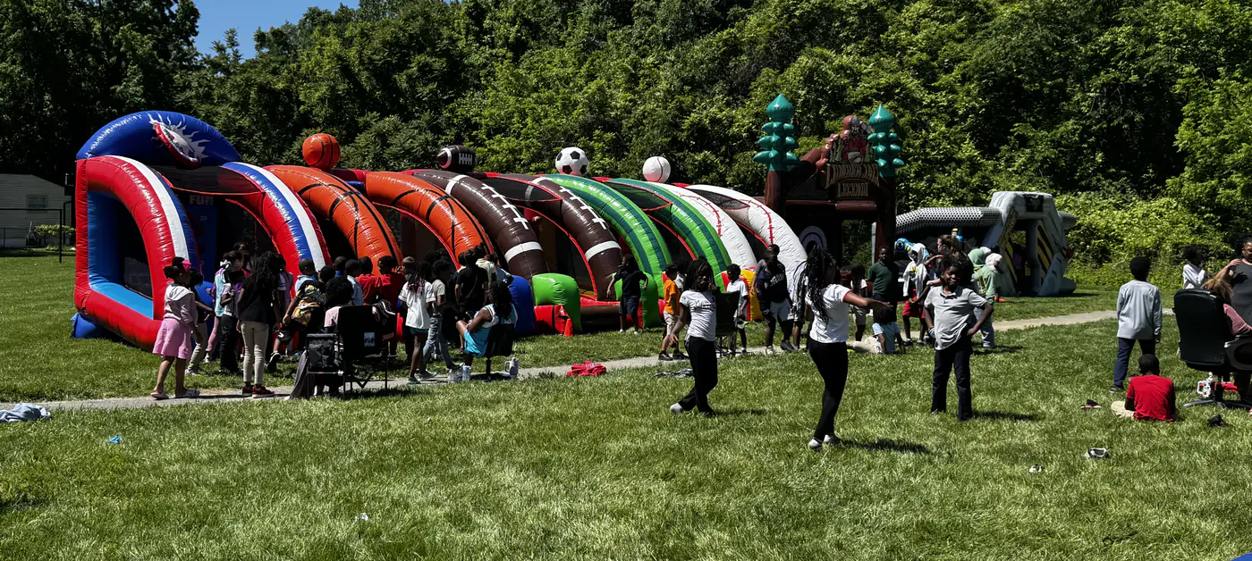 Students lined up along a row of Me 2 You inflatable sport games on a school field